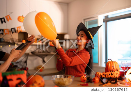 Halloween Joy. Woman in witch hat enjoying playful balloon interaction. Halloween Joy. Woman in witch hat enjoying playful balloon interaction. 130167615