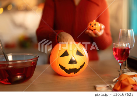 Halloween Fun. Woman preparing spooky treats with pumpkin decorations. Halloween Fun. Woman preparing spooky treats with pumpkin decorations. 130167625