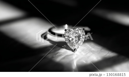 Heart shaped diamond ring with sparkling gemstone on silver band in dramatic black and white lighting, elegant jewelry close up 130168815