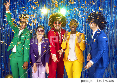 Funny group of happy young people dressed in bright business suits, curly wigs and colorful large glasses with rhinestones. 130170380