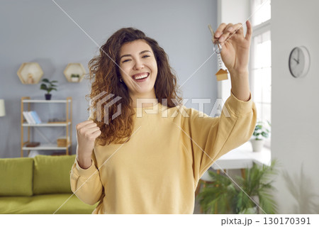Portrait of a young happy smiling pretty woman with keys in her hands standing at home. 130170391