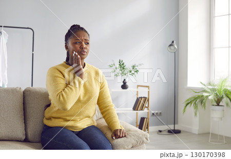 Woman with severe toothache touches her swollen cheek. 130170398