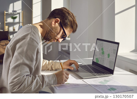 Professional cartographer working with printed cadastral map at table on his workplace. 130170507