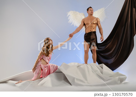 Emotive moment between angel and mortal in artistic performance setting 130170570