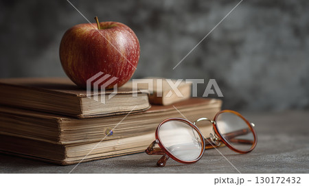 Stack of books with apple and reading glasses create warm and studious feeling, representing thirst for knowledge 130172432