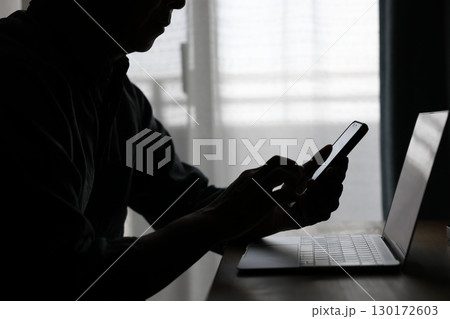 パソコンの前でスマホを使う男性 パソコンの前でスマホを使う男性 130172603