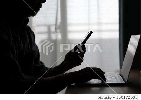 パソコンの前でスマホを使う男性 パソコンの前でスマホを使う男性 130172605
