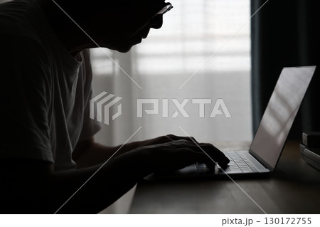 暗い部屋でパソコンを使う男性 130172755