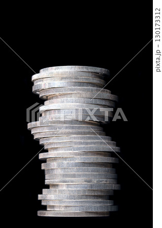 Column of zigzag stacked silver coins, against black background. Stacked circulated silver bullion coins, with reeded edges, of one troy ounce of 99.9 percent pure silver each. 999 fine silver coins. Column of zigzag stacked silver coins, against black background. Stacked circulated silver bullion coins, with reeded edges, of one troy ounce of 99.9 percent pure silver each. 999 fine silver coins. 130173312