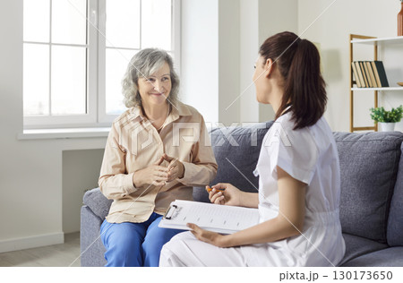 Caring kind nurse, geriatric medicine caretaker asking old woman nursing home resident, senior adult 130173650