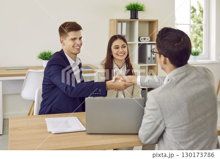 Happy family couple buy a house, sign a contract agreement and shake hands with their realtor 130173786