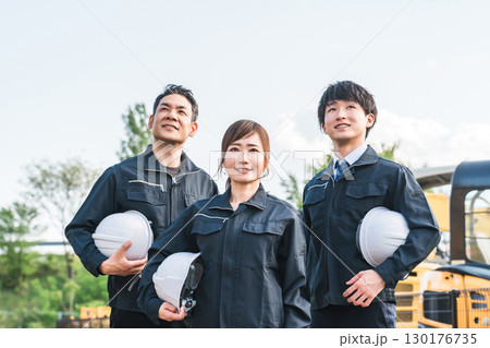 重機の前にいる作業着姿の建設業・建築業の作業員男女 130176735