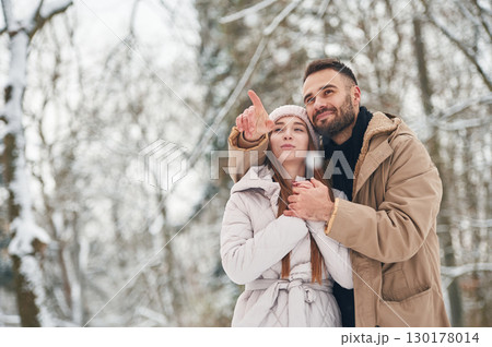 Showing and discovering new places. Lovely couple have a walk in the winter forest Showing and discovering new places. Lovely couple have a walk in the winter forest 130178014