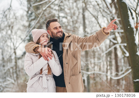 Showing and discovering new places. Lovely couple have a walk in the winter forest Showing and discovering new places. Lovely couple have a walk in the winter forest 130178016