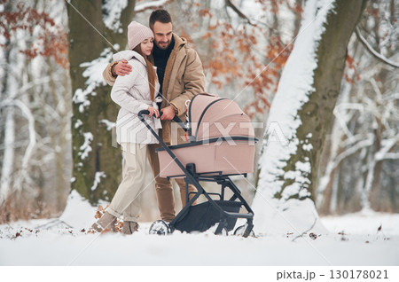 Mother and father with pram. Lovely couple have a walk in the winter forest 130178021