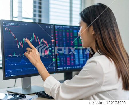 株価の推移を見つめ指さす若いビジネスパーソン　トレーダー　女性投資家 130178063