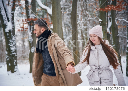 Holding hands. Lovely couple have a walk in the winter forest Holding hands. Lovely couple have a walk in the winter forest 130178076