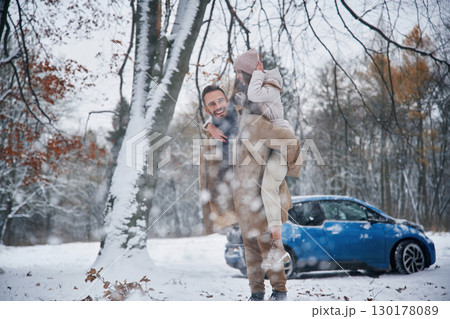Holding woman. Happy couple having a walk in winter forest. Blue car is parked Holding woman. Happy couple having a walk in winter forest. Blue car is parked 130178089
