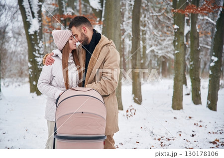 Parents with pram. Lovely couple have a walk in the winter forest 130178106