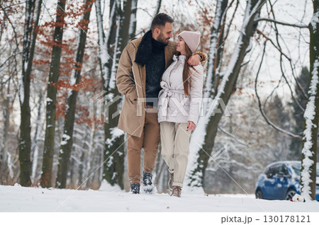 Lovely people. Happy couple having a walk in winter forest. Blue car is parked Lovely people. Happy couple having a walk in winter forest. Blue car is parked 130178121