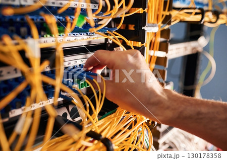 Close up view of hand that fixing internet. Young man is working with equipment and wires in server room Close up view of hand that fixing internet. Young man is working with equipment and wires in server room 130178358