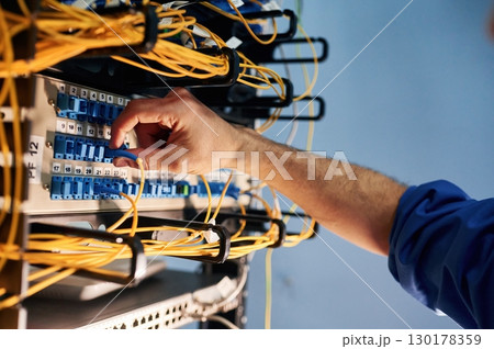 Close up view of hand that fixing internet. Young man is working with equipment and wires in server room Close up view of hand that fixing internet. Young man is working with equipment and wires in server room 130178359