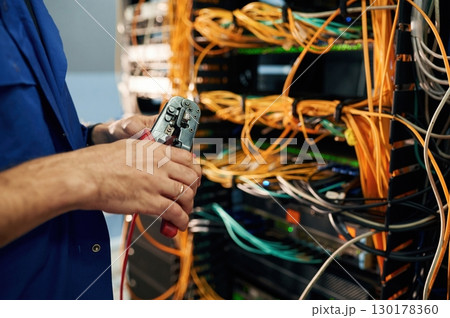Close up view of hand that fixing internet. Young man is working with equipment and wires in server room Close up view of hand that fixing internet. Young man is working with equipment and wires in server room 130178360