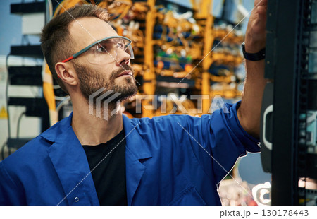 Handsome young man is working with internet equipment and wires in server room Handsome young man is working with internet equipment and wires in server room 130178443