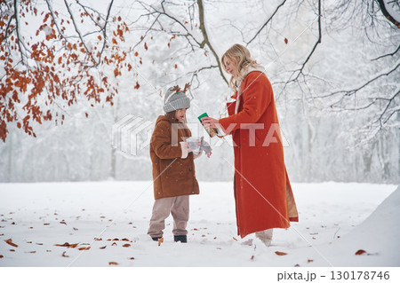 Pouring hot tea. Mother and her daughter is on the winter meadow and forest 130178746