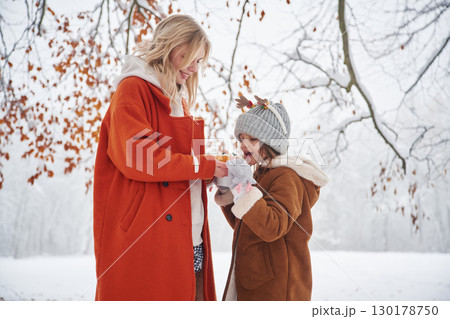 With sweet food. Mother and her daughter is on the winter meadow and forest 130178750