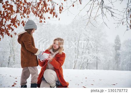 New year present in gift box. Mother and her daughter is on the winter meadow and forest 130178772