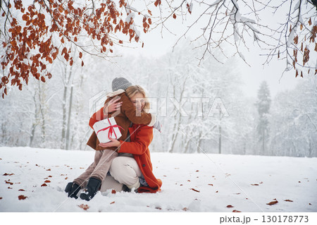 New year present in gift box. Mother and her daughter is on the winter meadow and forest 130178773