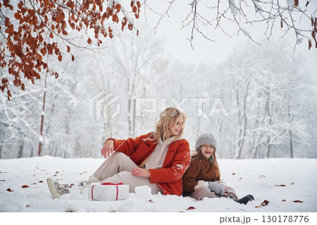 New year present in gift box. Mother and her daughter is on the winter meadow and forest 130178776