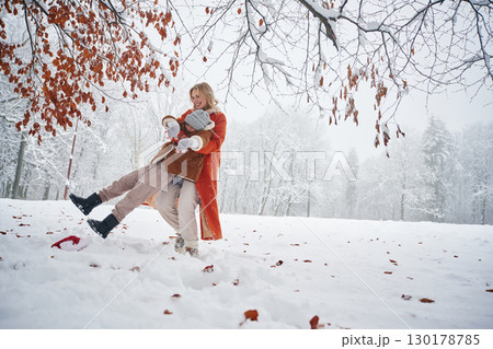 Playing and having fun. Mother and her daughter is on the winter meadow and forest 130178785