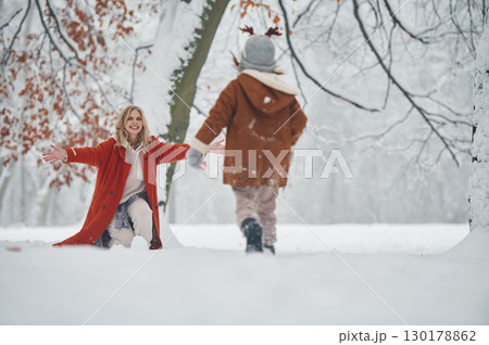 Hat with cute deer horns. Mother and her daughter is on the winter meadow and forest 130178862