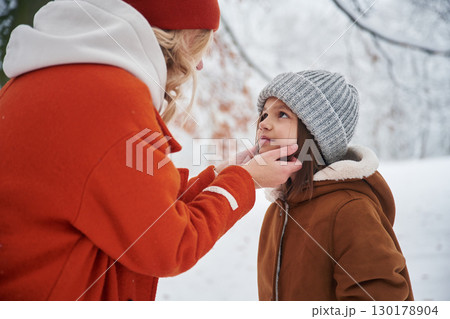 Taking care of girl. Mother and her daughter is on the winter meadow and forest 130178904