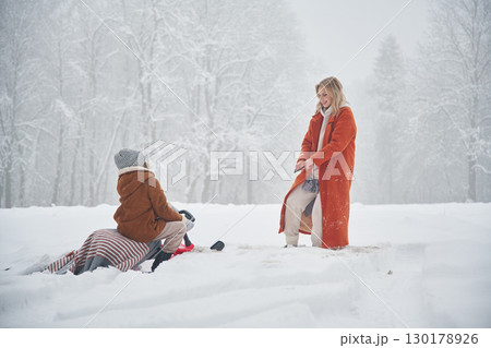 Sled ride. Mother and her daughter is on the winter meadow and forest 130178926