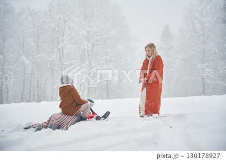 Sled ride. Mother and her daughter is on the winter meadow and forest 130178927