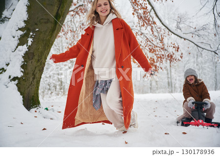 Having fun by sled ride. Mother and her daughter is on the winter meadow and forest 130178936