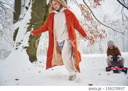 Having fun by sled ride. Mother and her daughter is on the winter meadow and forest 130178937