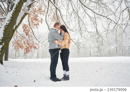 Beautiful couple are standing together on the snowy field of forest 130179006