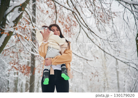 Woman with her little boy is in the winter forest on the meadow Woman with her little boy is in the winter forest on the meadow 130179020