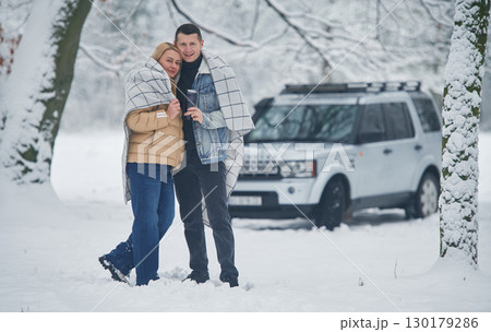 Embracing each other. Beautiful couple standing near the car in the winter forest Embracing each other. Beautiful couple standing near the car in the winter forest 130179286