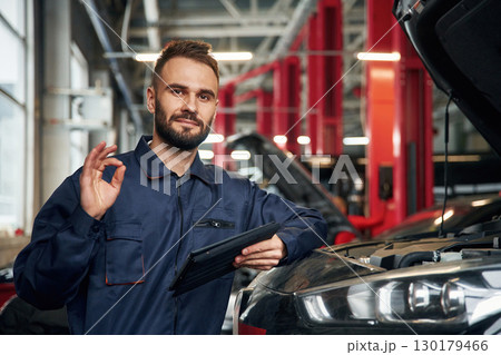 Using tablet. Car repairman is in the garage with automobile Using tablet. Car repairman is in the garage with automobile 130179466