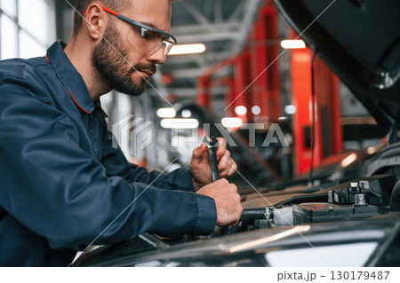 Hood is opened, fixing. Car repairman is in the garage with automobile Hood is opened, fixing. Car repairman is in the garage with automobile 130179487