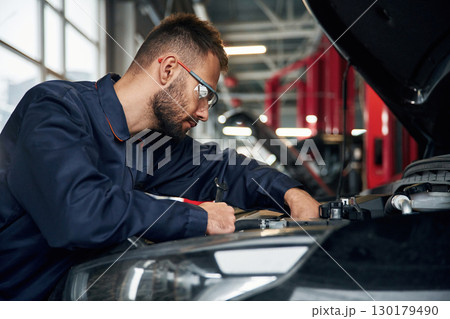 Car repairman is in the garage with automobile Car repairman is in the garage with automobile 130179490