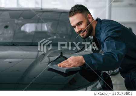 Process of polishing the surface with cloth. Car repairman is in the garage with automobile 130179603