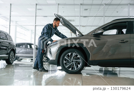 Fixing the vehicle. Side view. Car repairman is in the garage with automobile 130179624