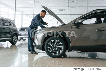 Focused on fixing the vehicle. Car repairman is in the garage with automobile Focused on fixing the vehicle. Car repairman is in the garage with automobile 130179629