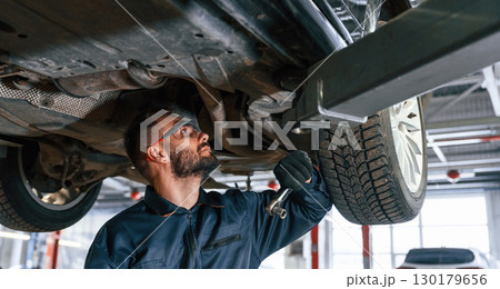 Fixing broken vehicle. Car repairman is in the garage with automobile 130179656